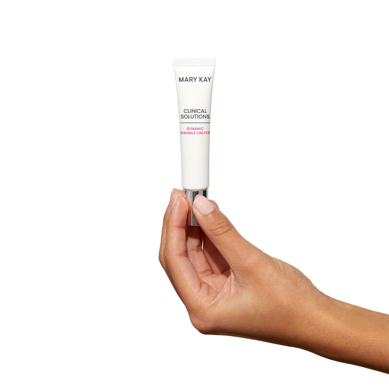 Medium-skinned hand holding tube of Mary Kay Clinical Solutions Dynamic Wrinkle Limiter against a plain background
