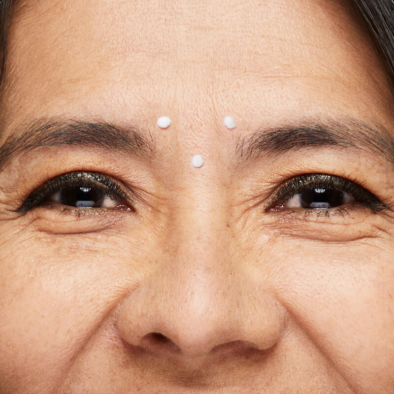 Close-up image of Dynamic Wrinkle Limiter placed in dots between eyebrows of mature brunette woman with smiling eyes
