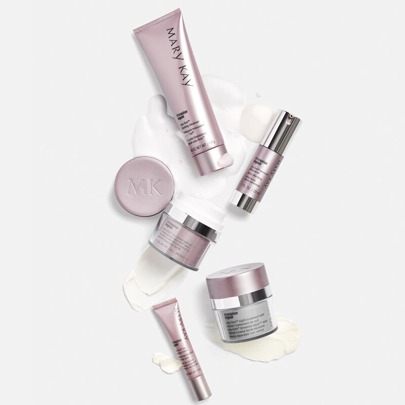 The Mary Kay TimeWise Repair Volu-Firm Set against a gray background with product formula smears behind each product.