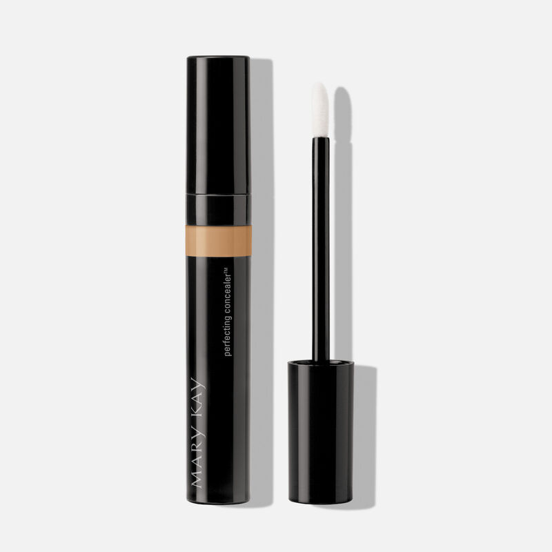 Tube of Mary Kay Perfecting Concealer in shade Light Bronze with cap on next to accompanying applicator.