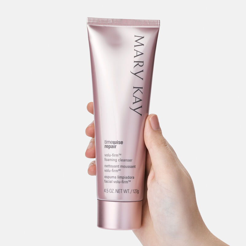 A hand holding a tube of TimeWise Repair Volu-Firm Foaming Cleanser from Mary Kay.