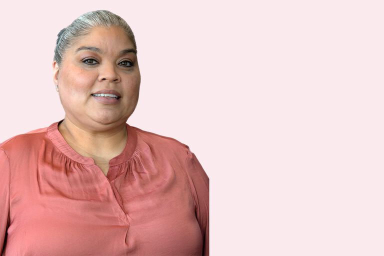 Person wearing a coral blouse against a light pink background