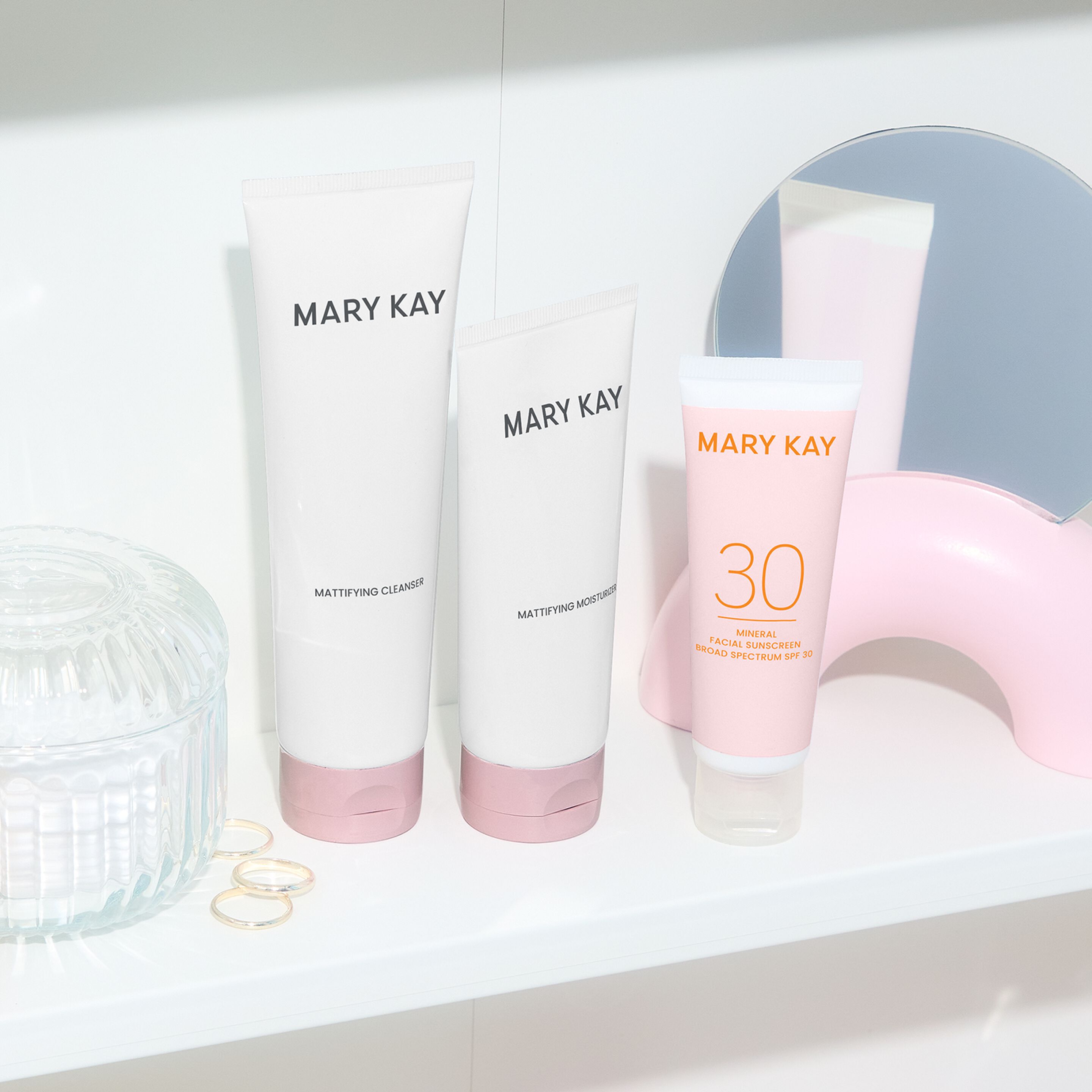 Los sets de cuidado de la piel hidratante y matificante de Mary Kay est&aacute;n colocados uno al lado del otro sobre una superficie de espejo con un fondo blanco.