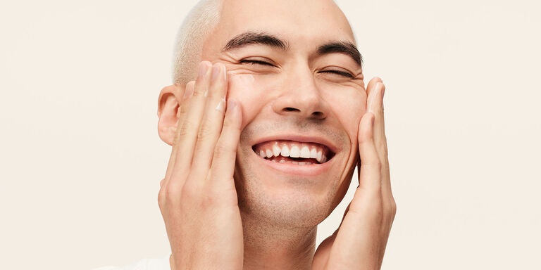 Male model applying MK Mens moisturizer to his face