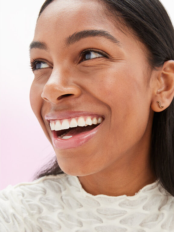 Mujer de piel oscura y cabello oscuro, con maquillaje natural y sonrisa radiante.