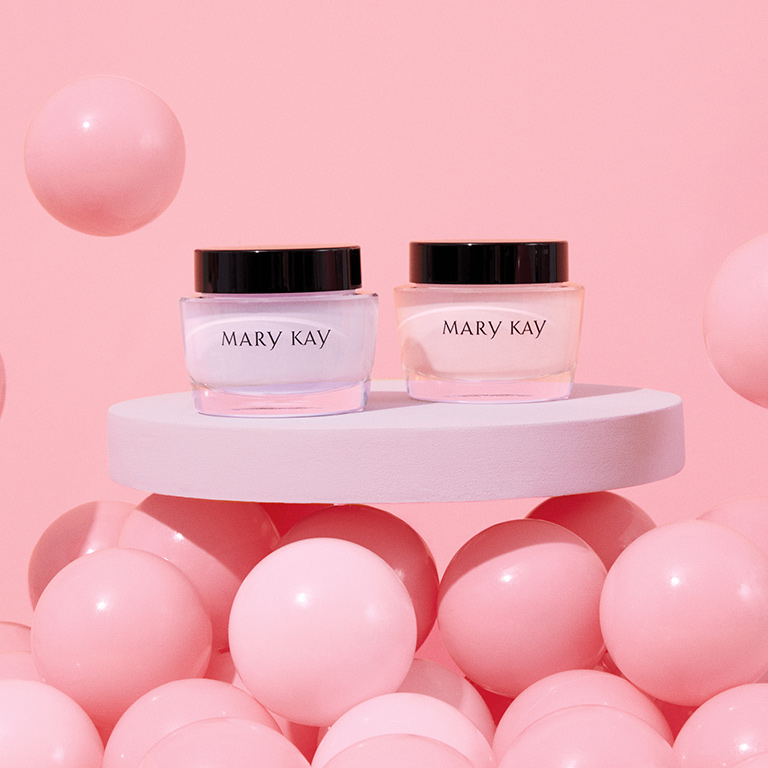 Jars of Mary Kay Oil Free Hydrating Gel and Mary Kay Intense Moisturizing Cream are placed on a white table surrounded by pink balloons.