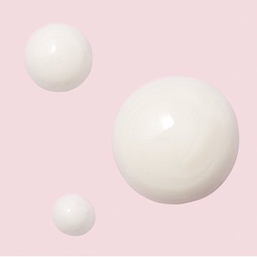 Gotas de la Loci&oacute;n Facial Regeneradora C + E TimeWise&reg; sobre un fondo rosa.