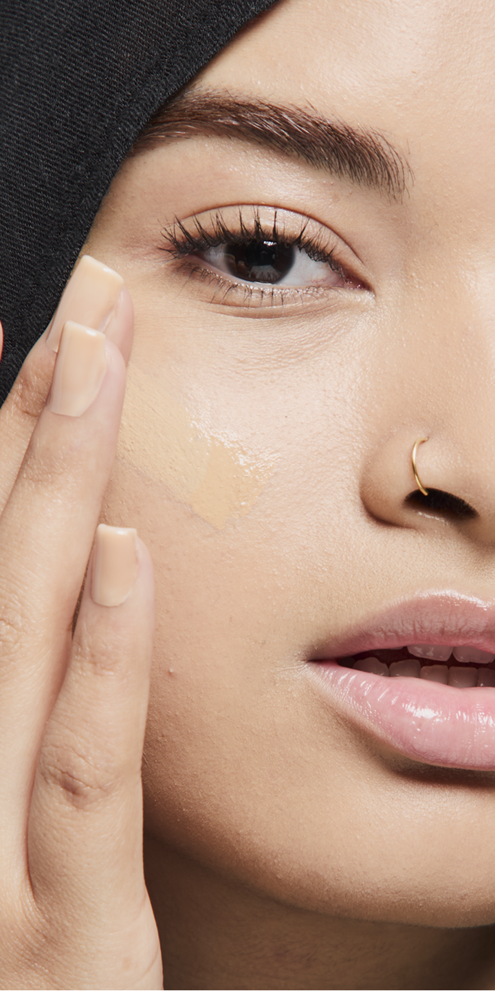 Modelo de tono de piel medio aplicando base de maquillaje.