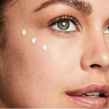 Mujer con tres puntos de la Loci&oacute;n Facial Regeneradora C + E TimeWise&reg; aplicados en la mejilla.